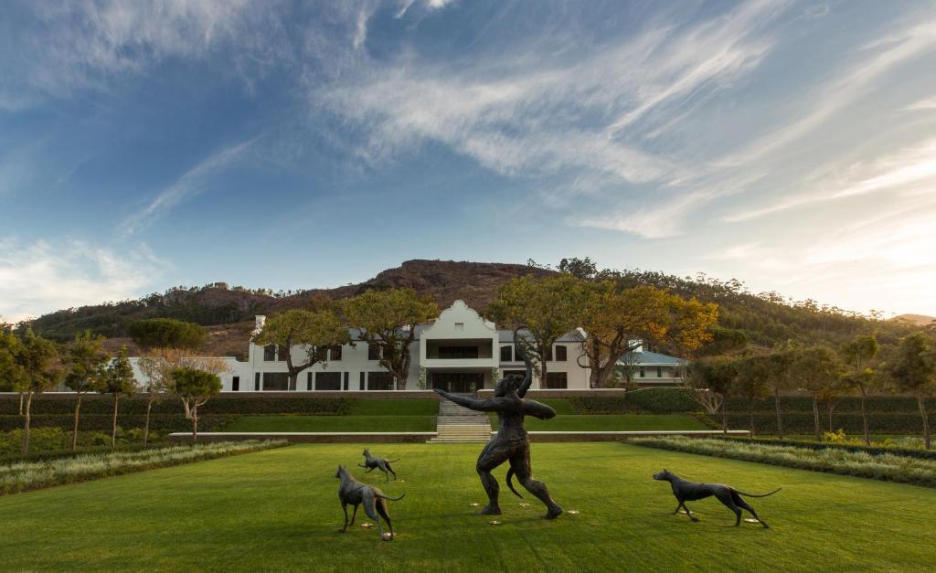 Eine Statue einer Frau und drei Hunde auf einem Feld in der Unterkunft Leeu Estates in Franschhoek