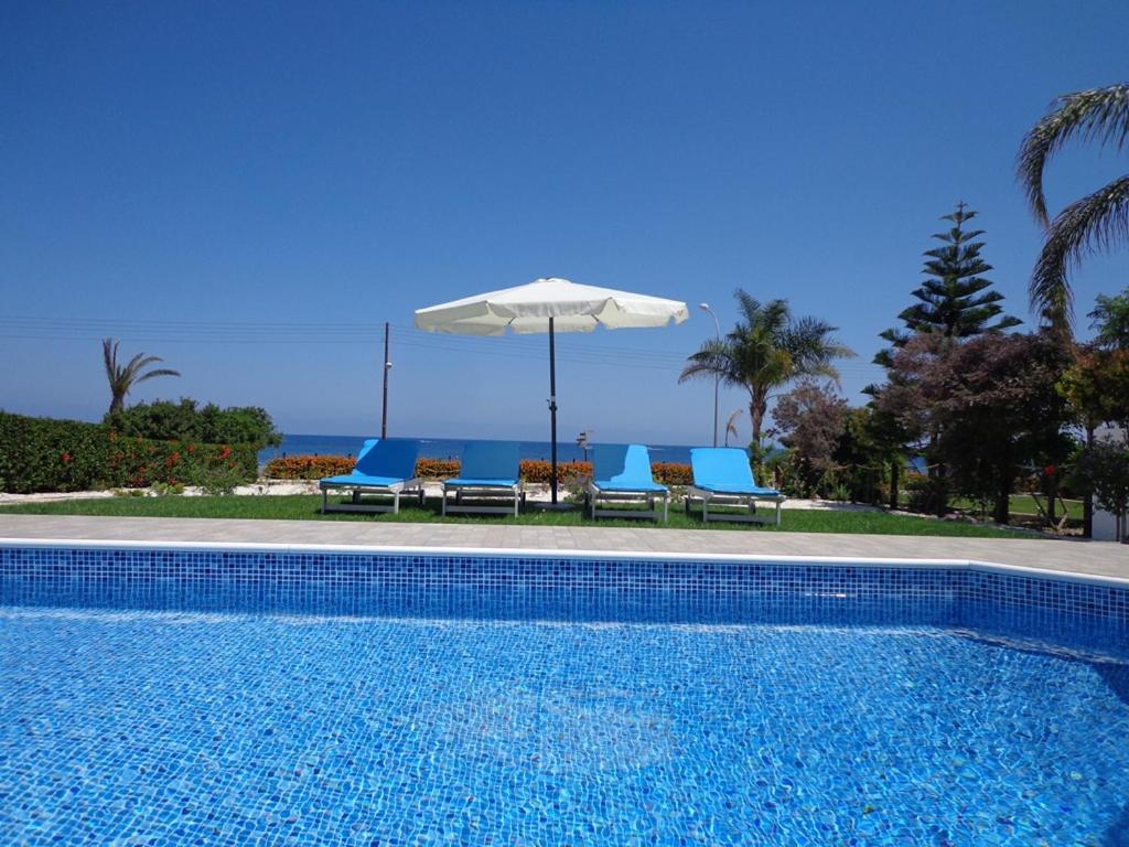 a swimming pool with two chairs and an umbrella at Latchi Riviera Beach Villa No.2 in Polis Chrysochous