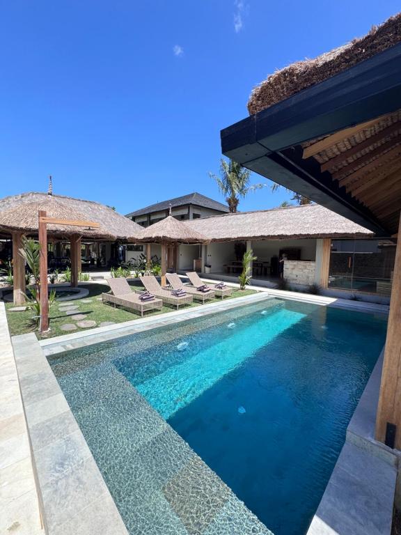 a swimming pool with chairs and a house at Baha Baha Villas West Sumbawa Yoyos Wellness Center, Gym, Yoga, Skate Park, Bar & Cafe in Sekongkang