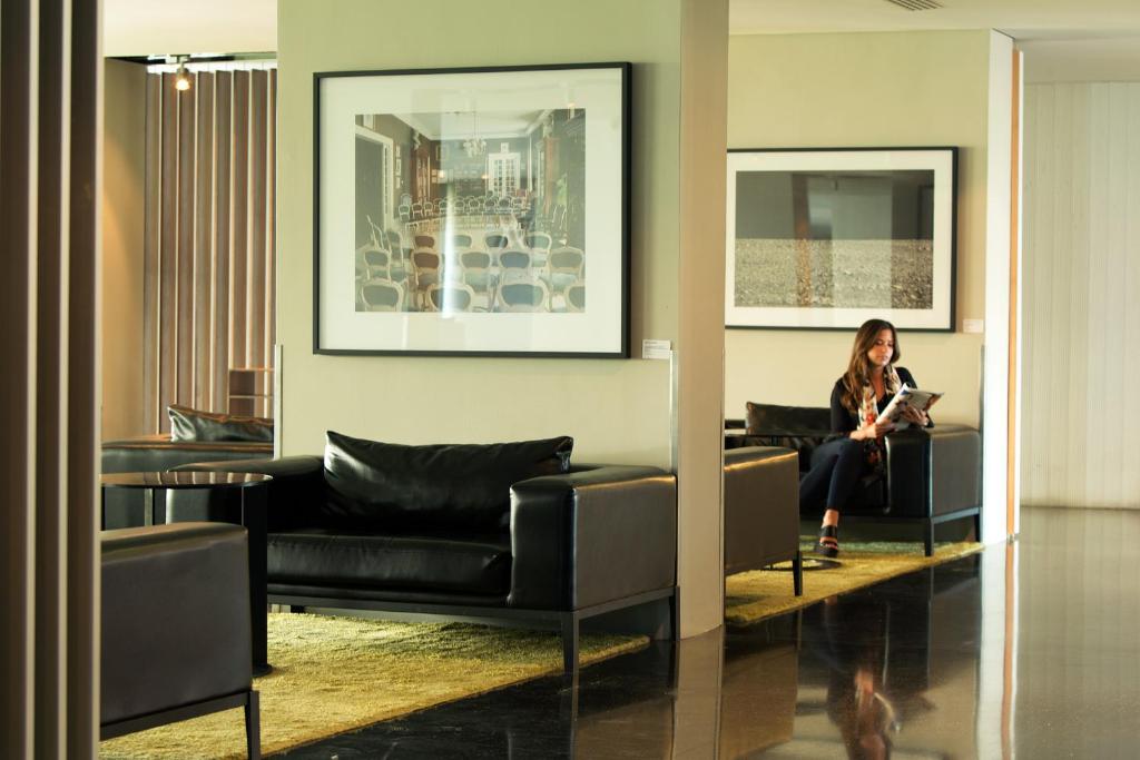 a woman sitting on a couch in a living room at Troia Design Hotel in Troia