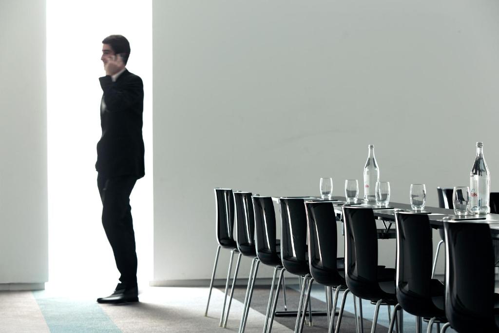 a man standing in front of a table with chairs at Troia Design Hotel in Troia