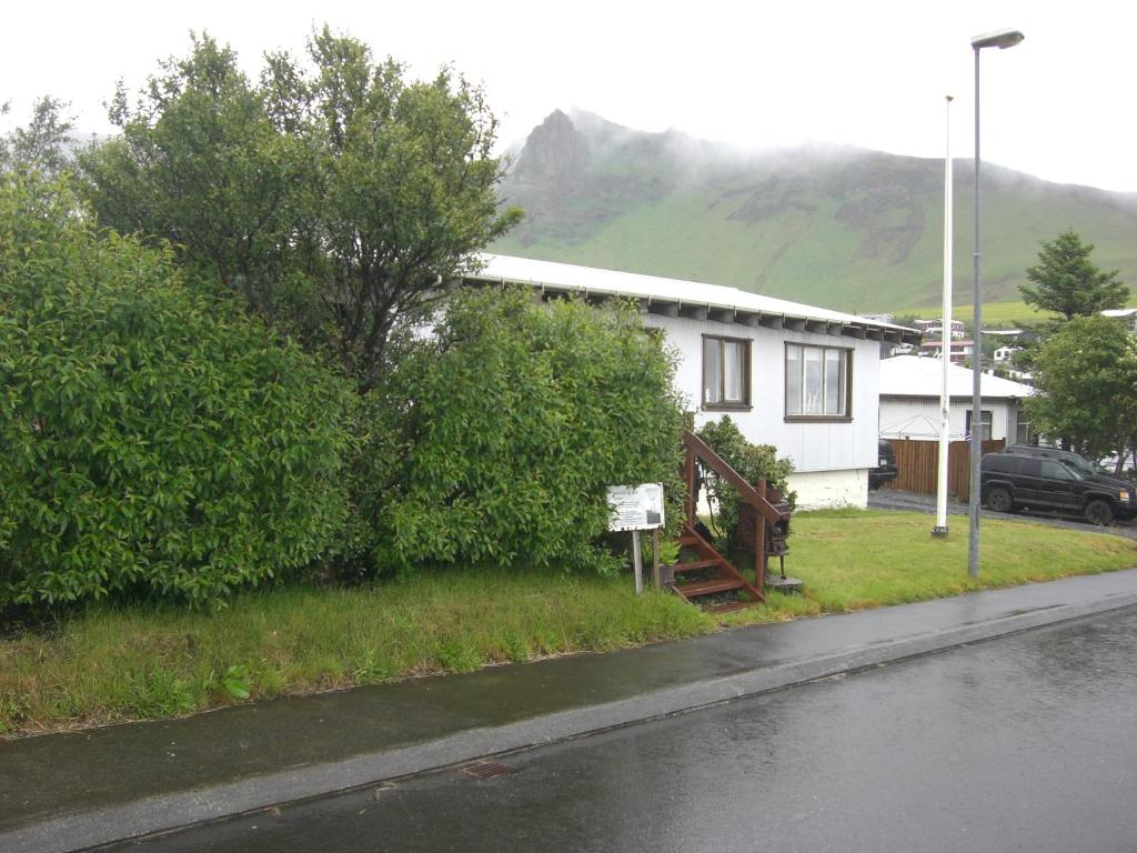 a house on the side of a street with a tree at Guesthouse Galleri Vík in Vík