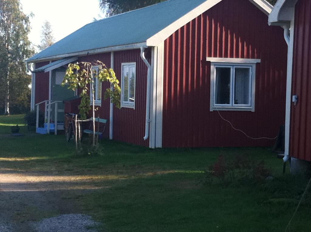 uma casa vermelha com uma árvore em frente em Lodge åstön em Söråker