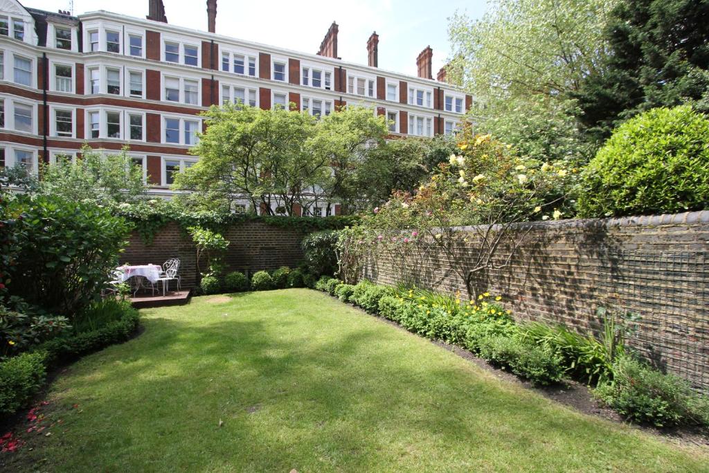 a garden in front of a brick wall and a building at Ridgemount Hotel in London