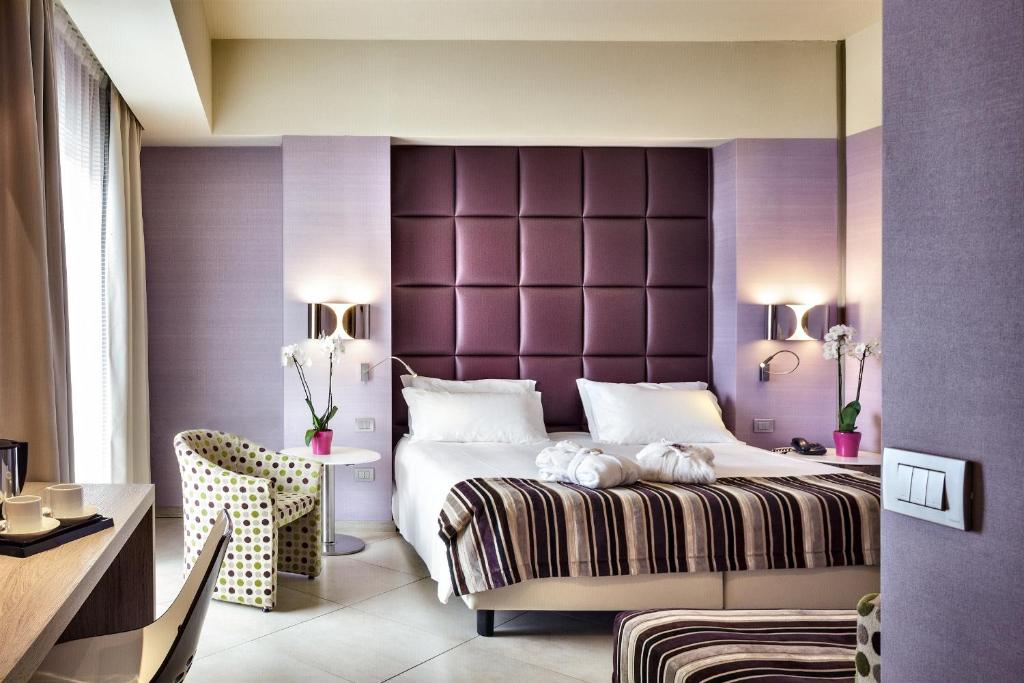 a bedroom with a large bed with a purple headboard at Jazz Hotel in Olbia