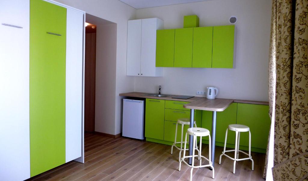 uma cozinha com armários verdes, uma mesa e bancos em Maironio apartamentas em Palanga
