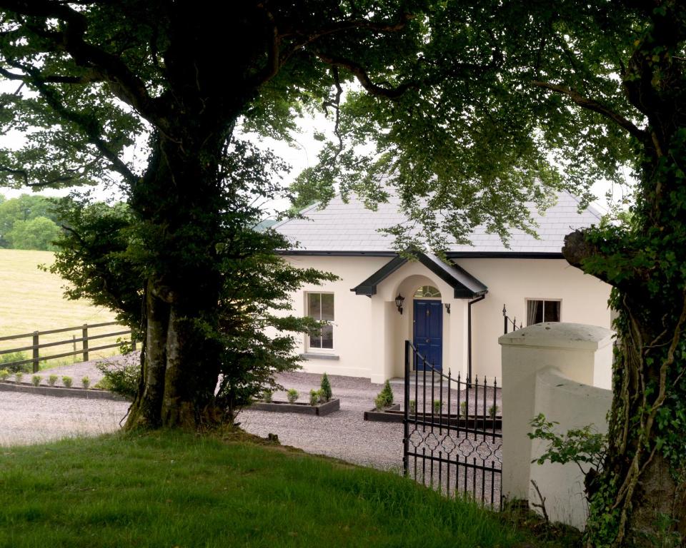 a white house with a blue door and a fence at The Gate Lodge Cannaway House in Macroom