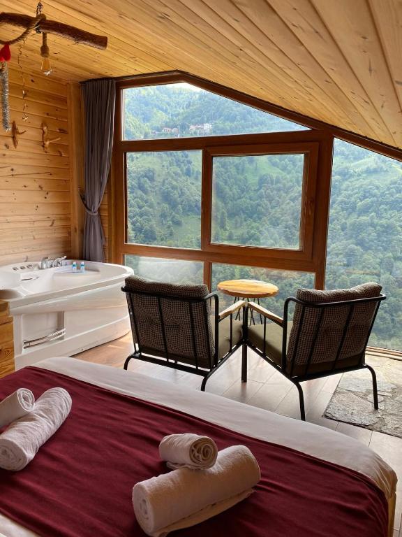 een slaapkamer met een bed, een bad en een raam bij Şana Suit Bungalov in Çamlıhemşin