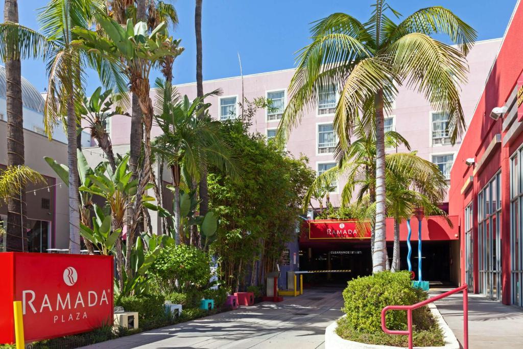 a street in front of a building with palm trees at Ramada Plaza by Wyndham West Hollywood Hotel & Suites in Los Angeles