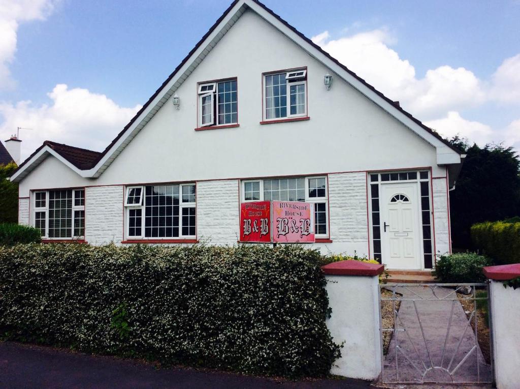 a white house with a sign in front of it at Riverside House in Roscommon