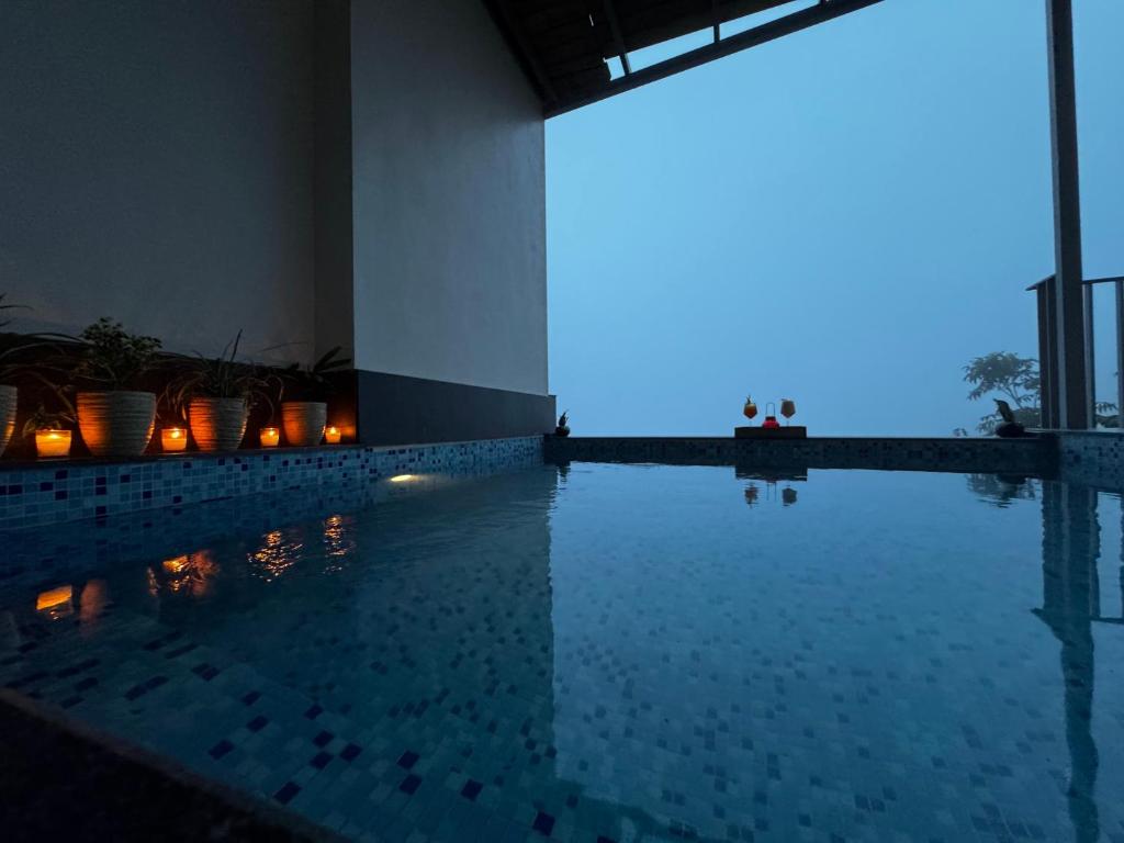 a swimming pool at night with candles in the water at OREN Kasauli in Kasauli