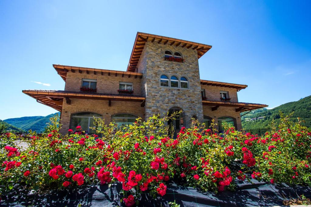 uma casa com flores vermelhas em frente em B&B La Torretta em Riolunato