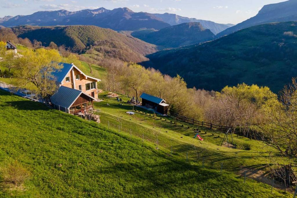 a house on a hill with mountains in the background at Holiday home Vila Bjelašnica in Bjelašnica