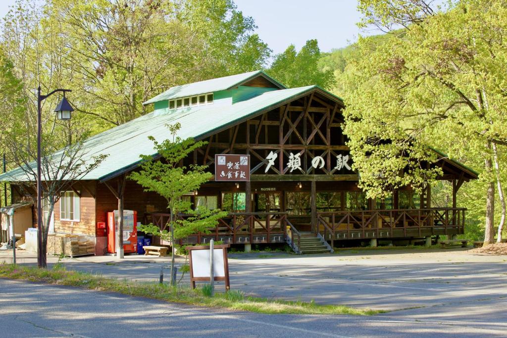 a large wooden building with a green roof at Yamanomura Campsite in Hida