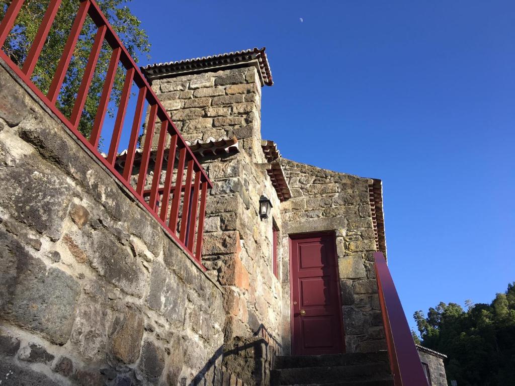 uma porta vermelha no lado de um edifício de pedra em Ribeira dos Caldeirões em Achada