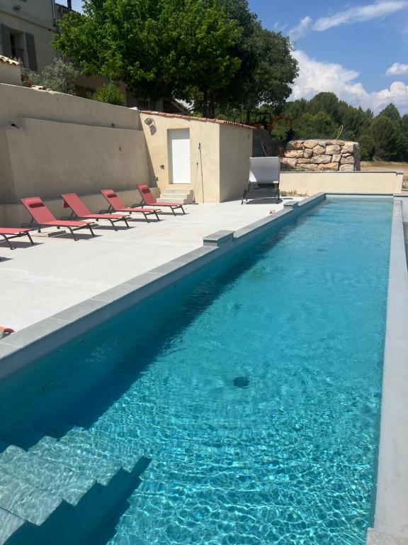 a swimming pool with chairs and blue water at Les Grandes Conches in Valensole