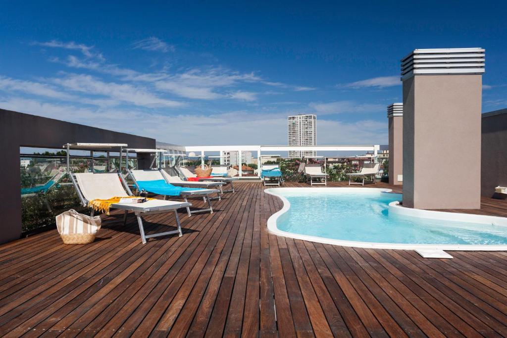 a deck with chairs and a swimming pool on a building at Residence Delfina in Rimini