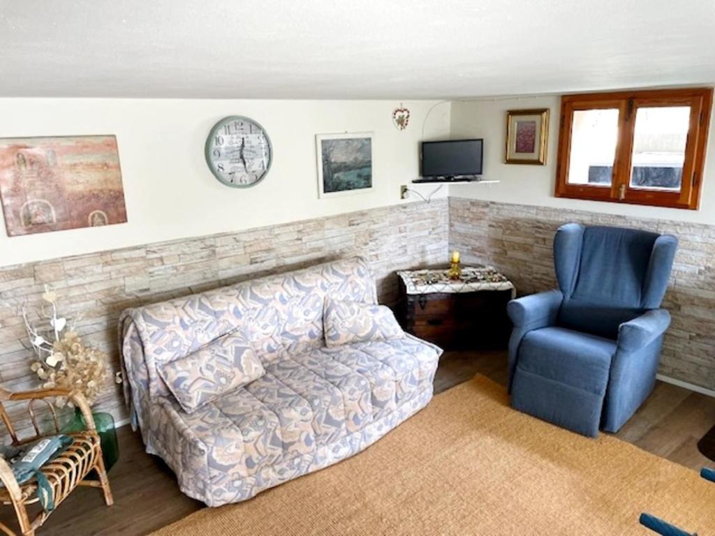 un soggiorno con divano, sedia e orologio di Chalet in Marliana near center a Marliana