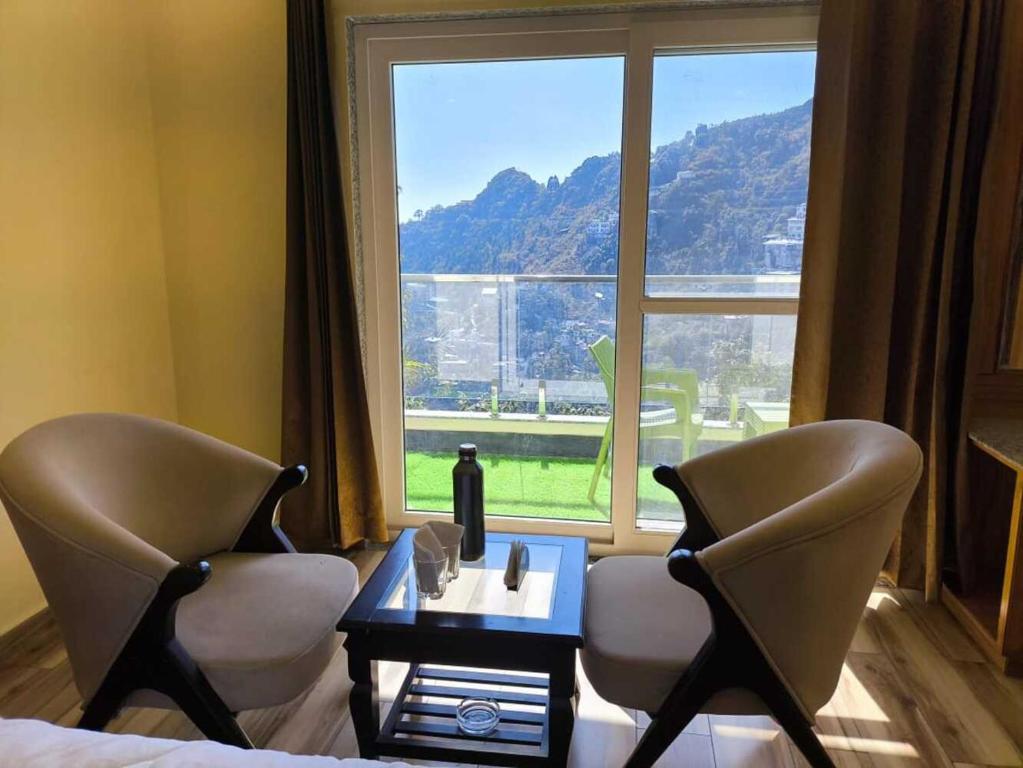 a room with two chairs and a table and a window at The Boho Mussoorie in Mussoorie