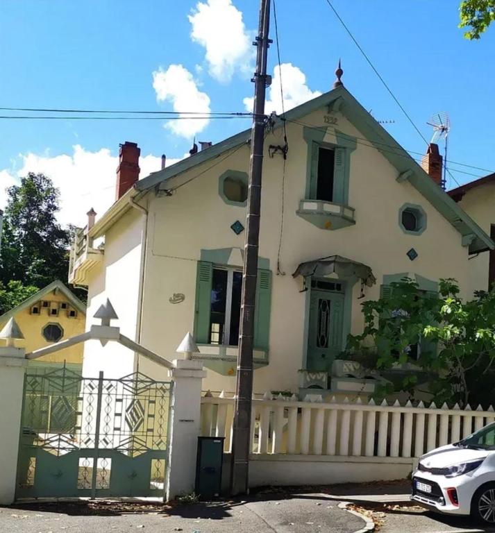 a white house with green trim and a fence at Charme et jardin in Toulouse