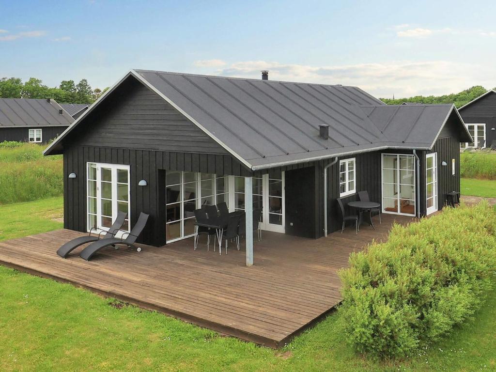 een groot zwart huis met een houten terras bij Holiday home near Nysted in Nysted