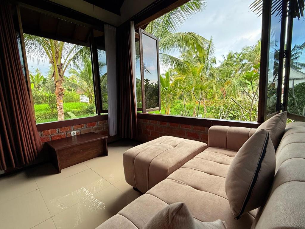 een woonkamer met een bank en grote ramen bij Mu Homestay in Tetebatu