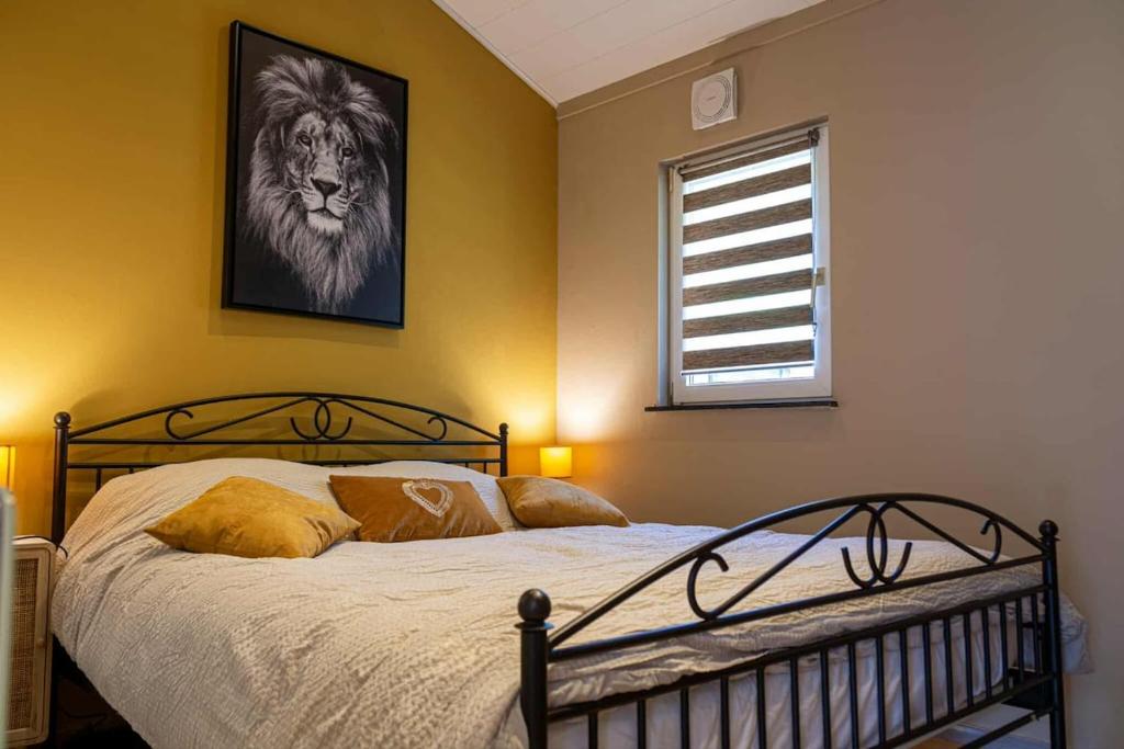 - une chambre avec un lit orné d'une photo de lion sur le mur dans l'établissement Le Rensy, à Ferrières
