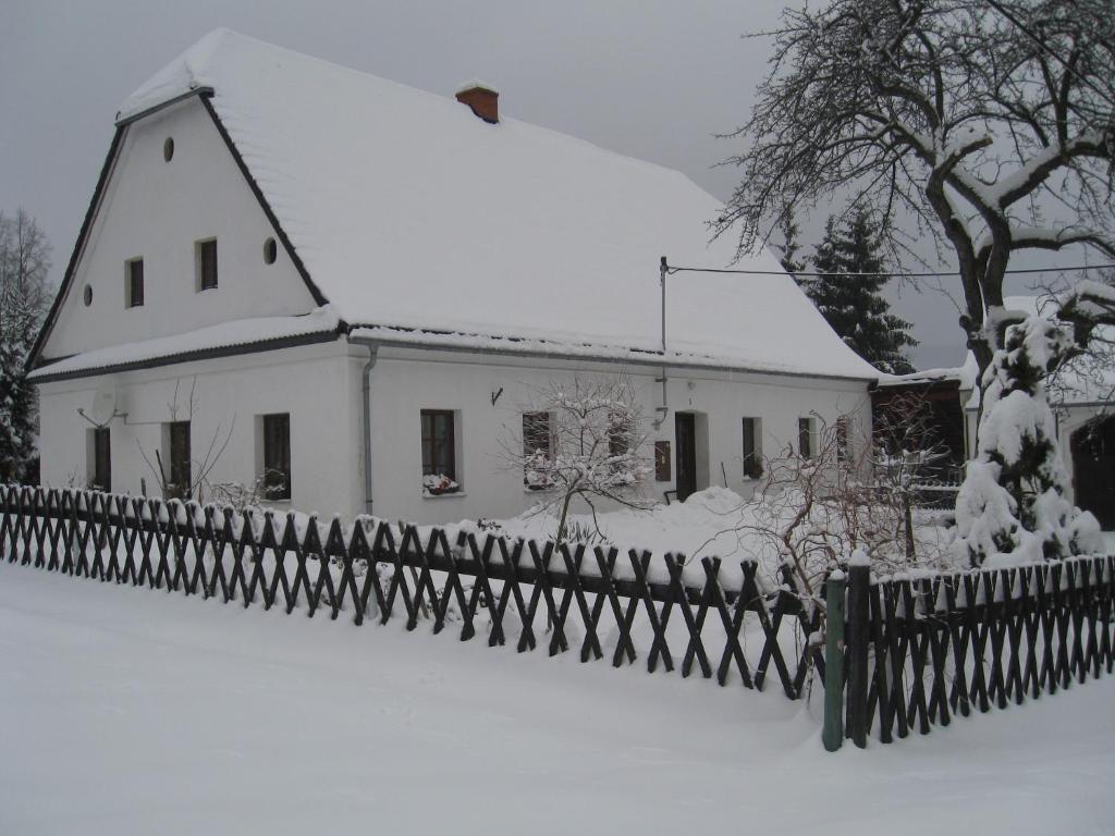 a house covered in snow next to a fence at Holiday Home in Zátor near Ještěd Ski Resort in Zátor