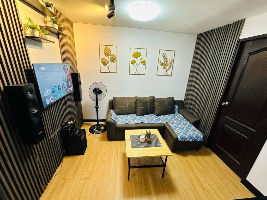 ein Wohnzimmer mit Sofa und Fernseher in der Unterkunft Reyes Haven - Urban Deca Marilao in Marilao