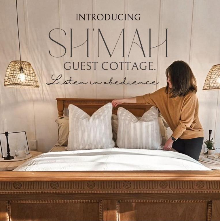 a woman is placing pillows on a bed at Sh'mah Guest Cottage in Paddock