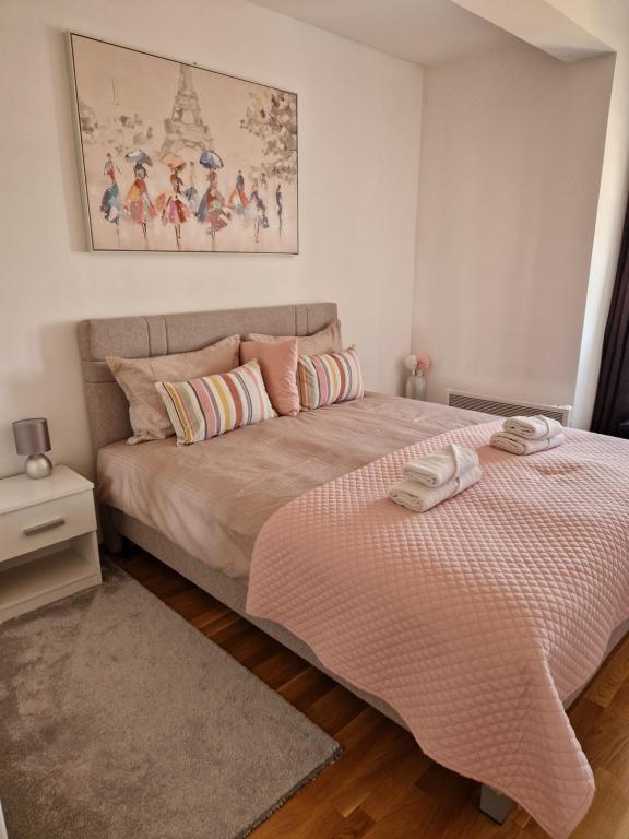 a bedroom with a large bed with a pink comforter at Apartman Iris in Pirot