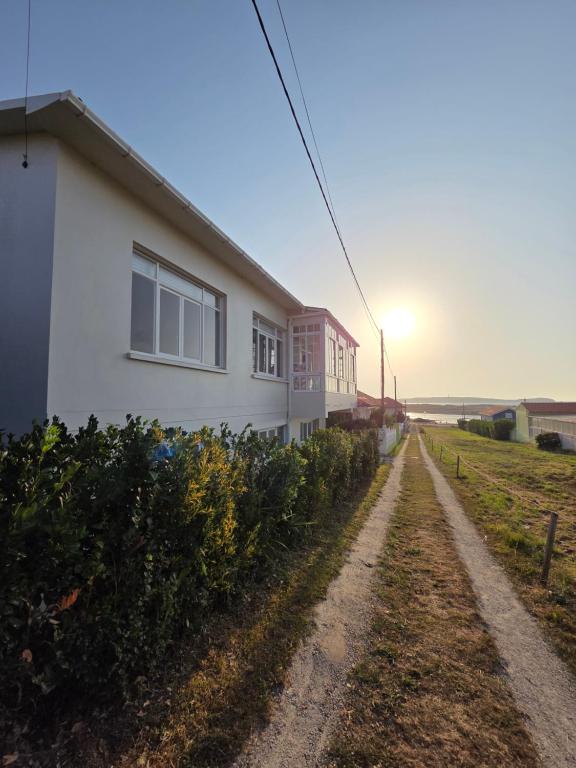 a house on a dirt road with the sun in the background at Casa frente al mar in Valdoviño