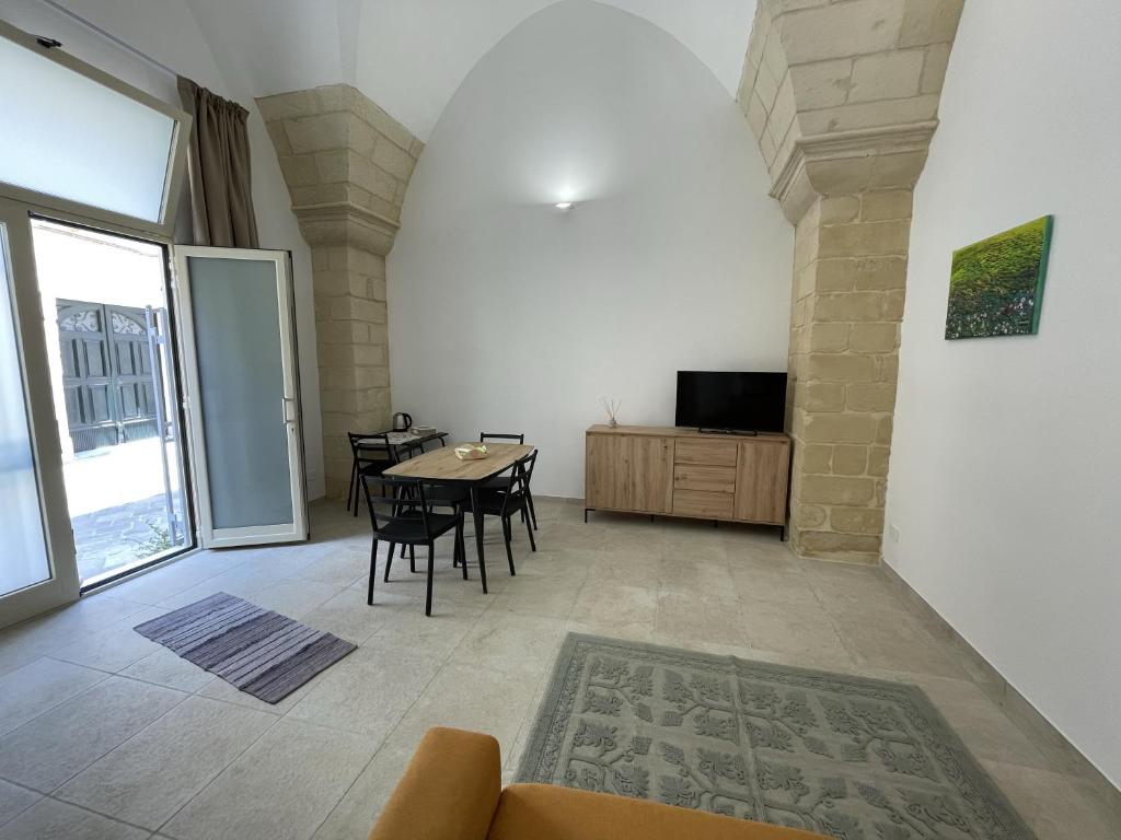 Una sala de estar con una mesa y sillas y un televisor. en Casa Sant'Ippolito, en Lecce