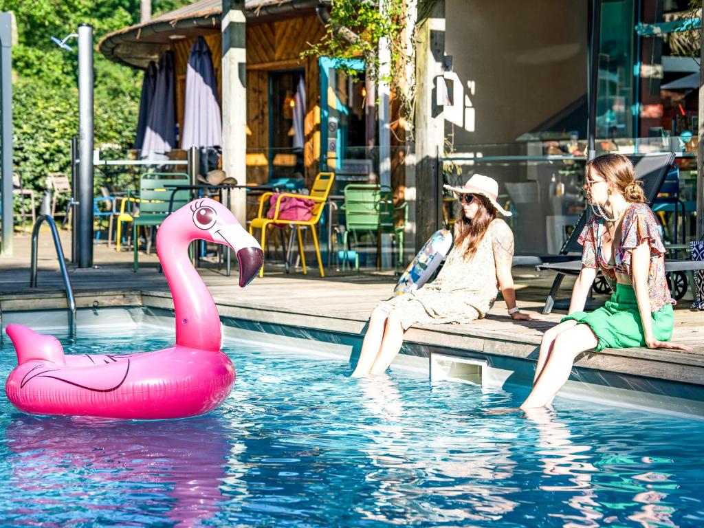 two women sitting on a bench in a pool with a pink swan at ibis Arcachon la Teste de Buch in La Teste-de-Buch