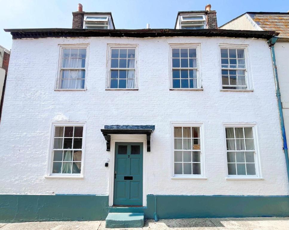 ein weißes Haus mit einer grünen Tür und Fenstern in der Unterkunft Admiralty House in Weymouth