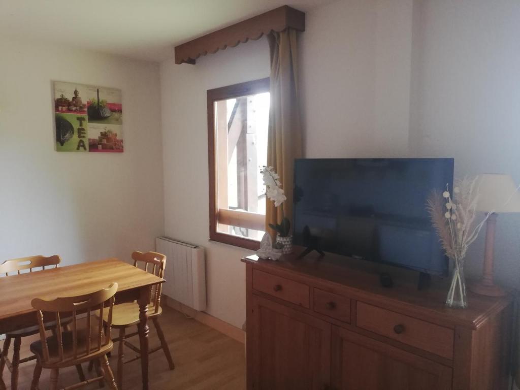 a living room with a dining table and a flat screen tv at Studio chaleureux de montagne in Ustou
