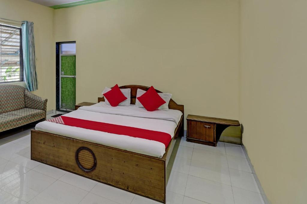 a bedroom with a bed with red pillows and a couch at Hotel O Green Hills Resort in Sopāra