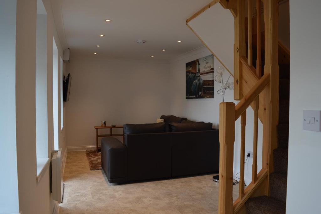 a living room with a black couch and a staircase at Worship Farm Accommodation in Redhill