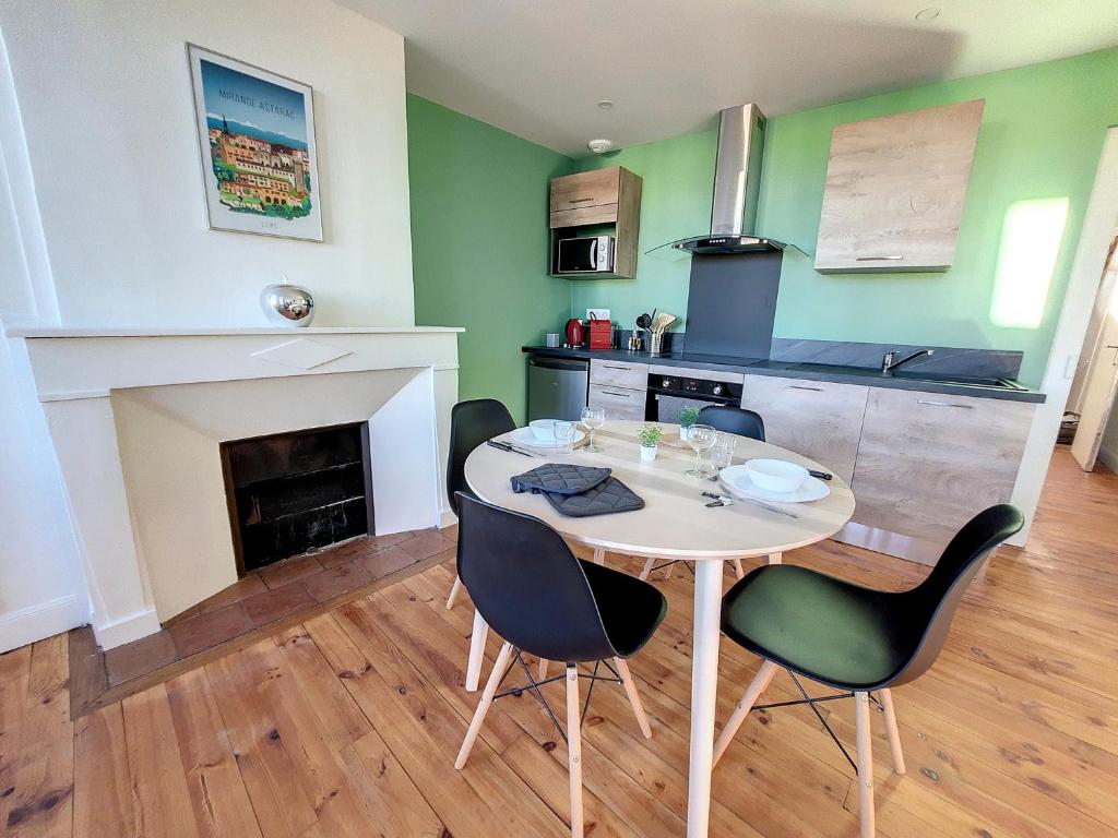 a dining room with a table and chairs and a fireplace at Les Arcades - Mirande Centre in Mirande