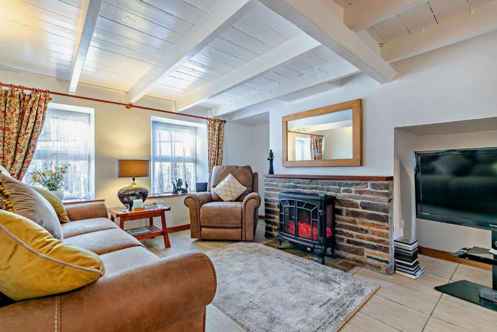 Una sala de estar con un sofá y una chimenea. en Victoria House - St Issey, en Saint Issey