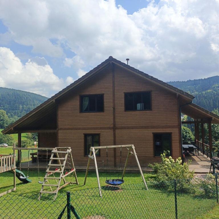 a house with a playground in front of it at Chalet Bois le Havre du sotrè Gérardmer Sauna panoramique jacuzzi 14 personnes et 1 bébé in Gérardmer