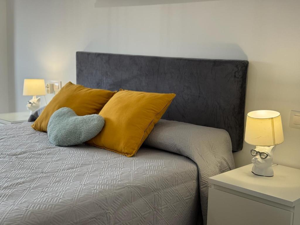 ein Bett mit einem gelben Kissen und einem grauen Kopfteil in der Unterkunft Campo de la Verdad Home Luxury in Córdoba