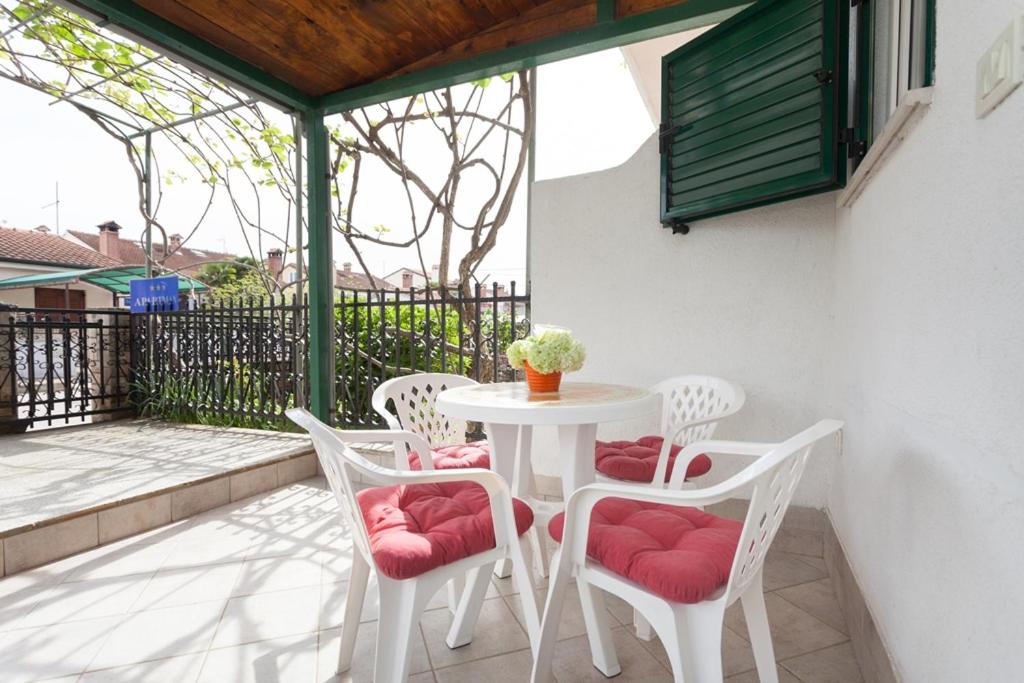 une table blanche et quatre chaises sur la terrasse dans l'établissement Apartment Darko, à Rovinj