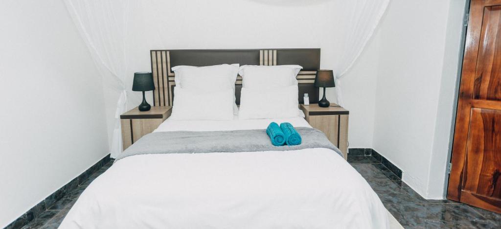 a bed with a pair of blue flip flops on it at Austin's Oasis Apartment in Livingstone
