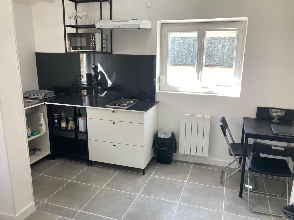 a kitchen with a counter top and a table and a window at Maisonnette indépendante in Morangis