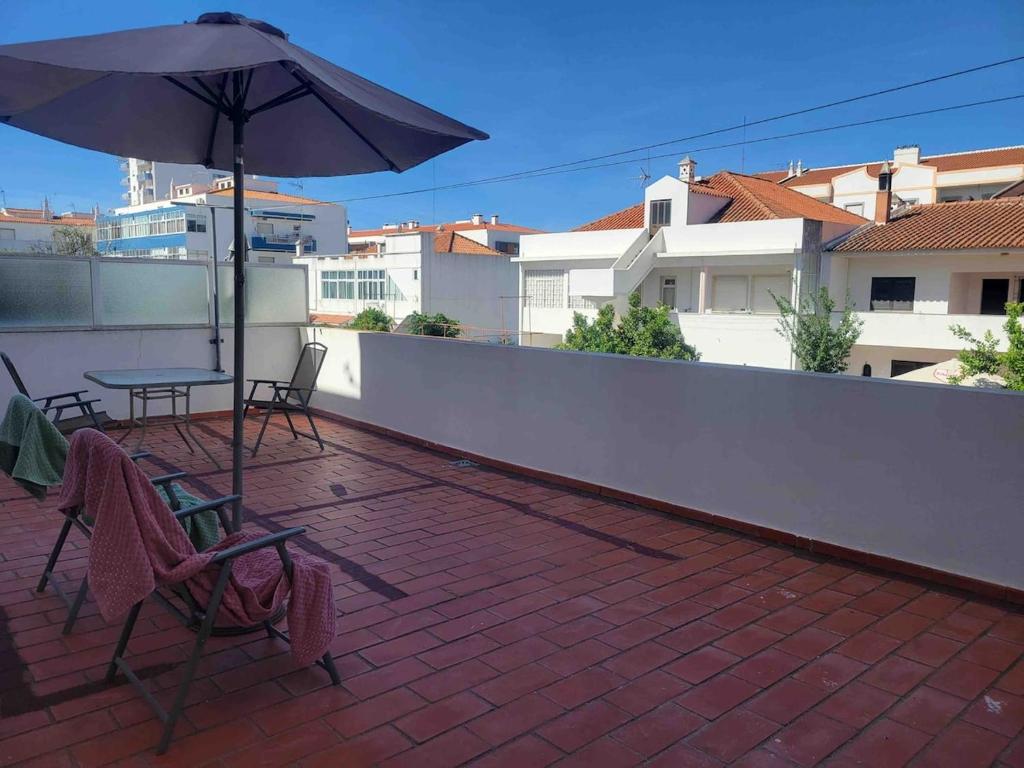 a patio with a table and an umbrella on a roof at Apartamento amplio T3 Sao Bras de Alportel in São Brás de Alportel