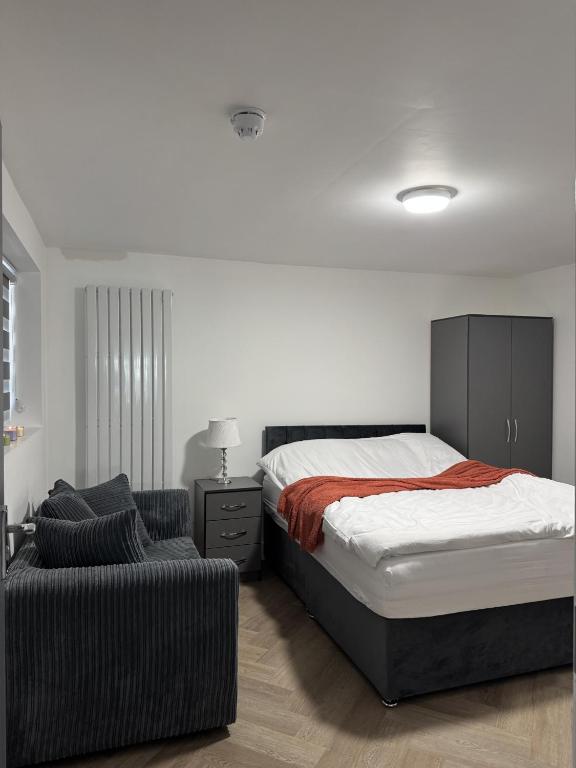 a bedroom with a bed and a chair at Old Ridgeway Hotel in Chingford