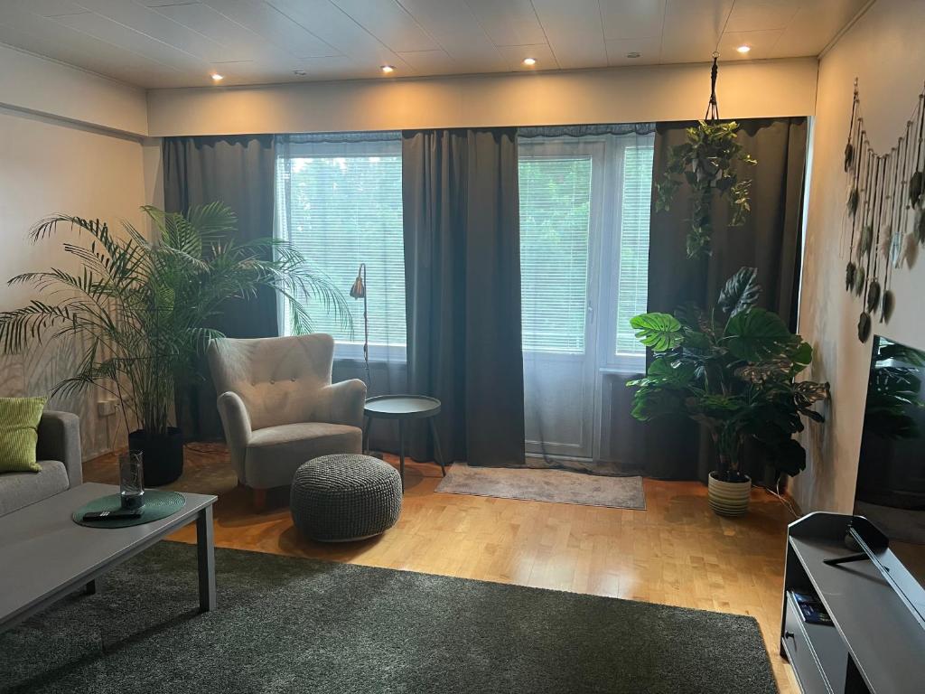 a living room with a couch and chairs and plants at Cityflat by Travel Center in Lappeenranta