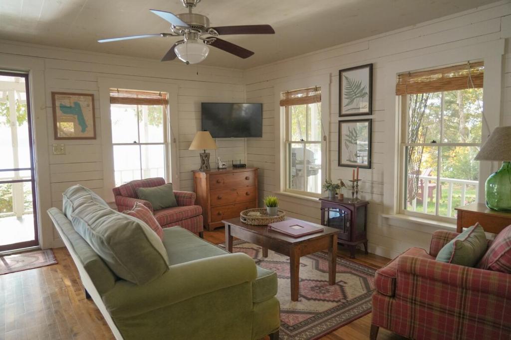 a living room with two couches and a table at Charming 1-bedroom Waterfront Cottage in Morgan VT in Morgan