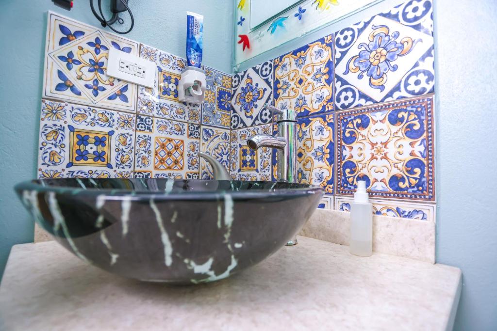 a bathroom with a sink and a tile wall at Denyse Home Cottage in Saint Johnʼs